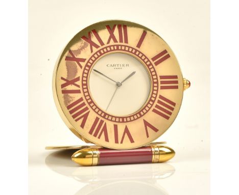 A Cartier Paris quartz folding travelling clock, of gilt metal circular form, the signed dial with outer red enamelled Roman 