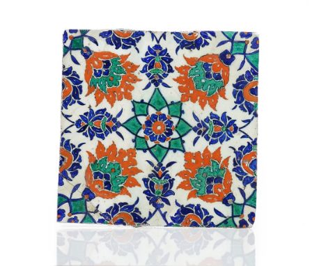 An Iznik pottery tile, circa 1580, painted in bole-red, green and cobalt-blue with central flower medallion surrounded by fou