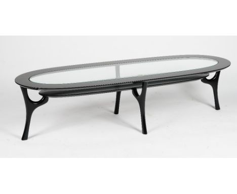 A black lacquered oval 'racetrack' coffee table, with glass inset top and undertier, on splayed legs, 152cm wide x 38cm high.