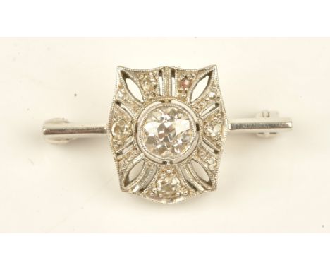 A diamond brooch in a pierced curved panel shaped design, mounted with the principle cushion shaped diamond to the centre and