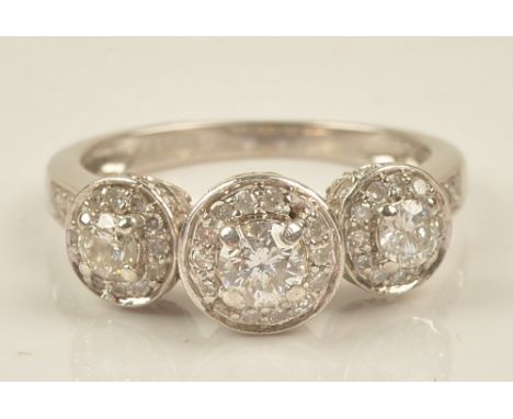 A white gold and diamond set ring, in a triple cluster design, claw set with the principal circular cut diamonds to the centr