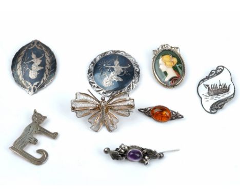 A group of mostly silver jewellery, comprising; eight brooches, a reconstituted amber pendant with a neckchain, seven further