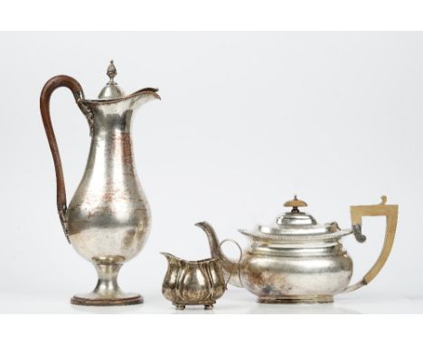 A silver cream jug raised on four bun feet, Sheffield 1905, weight 85gms, a plated teapot having wooden fittings and a plated