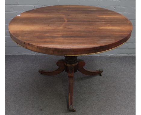 A Regency rosewood gilt metal mounted breakfast table, the circular tilt-top on a ring turned pillar and tripod base with cas