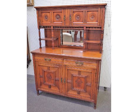 An Aesthetic Movement walnut side cabinet, with four flower carved doors over bevelled mirror, the base with a pair of drawer