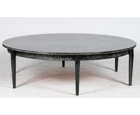 A circular ebonised low centre table, with ceruse finish, on rounded tapering legs, 156cm diameter. 