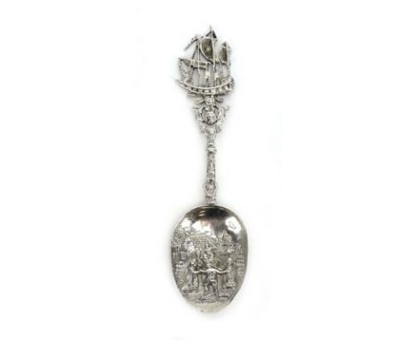 A Dutch metalware caddy spoon with galleon finial and repousse decorated bowl depicting a village scene, l. 13 cm CONDITION R