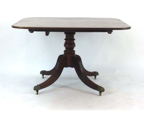 A 19th century mahogany breakfast table, the tilt-top on a turned column with four splayed legs, brass claw feet and castors,