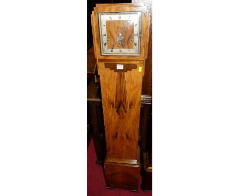 An Art Deco figured walnut grand-daughter clock, having square silver chapter ring, striking and chiming movement, raised on 