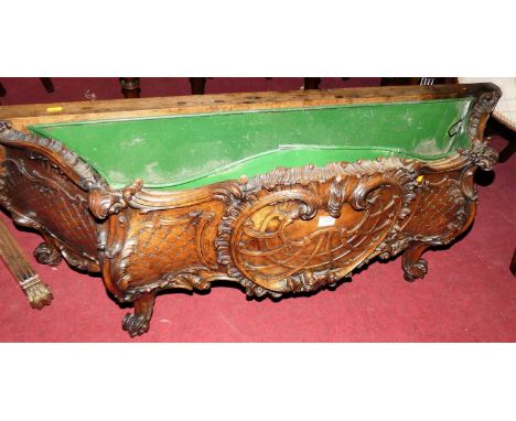 A 19th century provincial French heavily carved walnut low planter, of serpentine bombe shaped form, profusely floral carved,