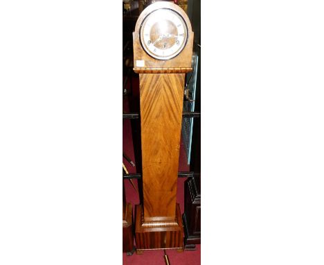 An Art Deco figured walnut grand-daughter clock, the dome top with silver chapter ring, striking and chiming movement to step