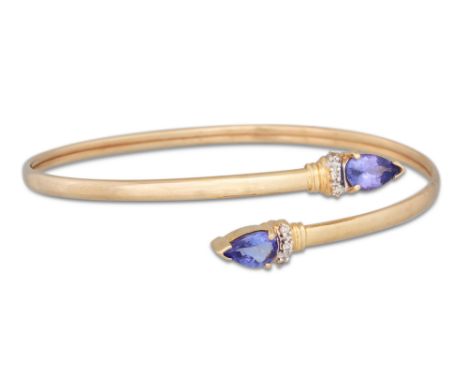 A TANZANITE AND DIAMOND SET BANGLE, mounted in 14ct gold
