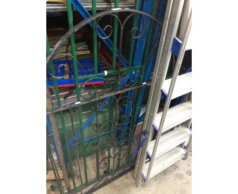 A black painted wrought iron garden gate. 