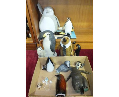 A collection of sixteen wood, glass, ceramic and composite penguin figures,&nbsp;a ceramic tile and a glass seal paperweight.