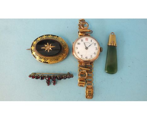 A locket-back onyx set mourning brooch (onyx cracked, enamel af), a ladies 9ct gold cased wrist watch (af), a garnet brooch a