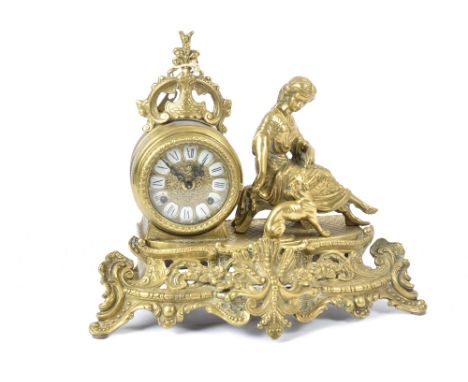 An early 20th Century brass eight day mantle clock, with an enamel dial with Roman numerals and surmounted with a woman and a