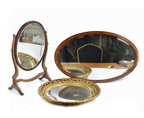 A group of three mirrors, comprising an Edwardian mahogany oval wall mirror, satinwood inlay, ebony and boxwood stringing, be
