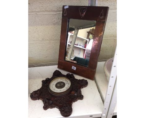 An Art Deco copper framed wall mirror together with a Victorian carved oak wall barometer.