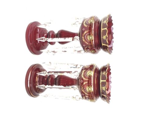 Pair of Victorian ruby glass lustre vases, each with hollow baluster stem, domed base, gilt and enamel decoration, hung with 