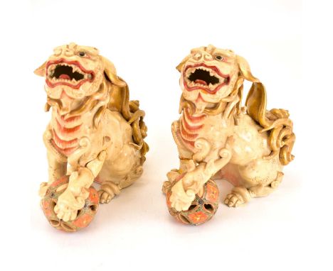 Two ceramic Dogs of Fo, each holding a Satsuma-style pierced ball, 17 x 16.5cm (2).Condition Report: Both seem to have had so
