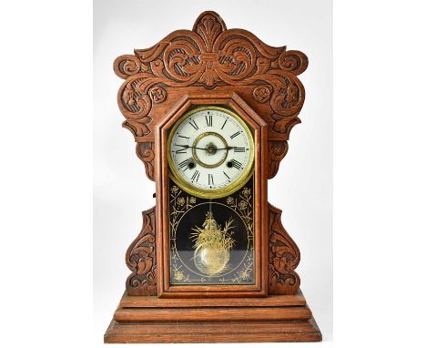 NEW HAVEN CLOCK CO; an American oak cased mantel clock, the white enamelled dial set with Roman numerals and inscribed with t