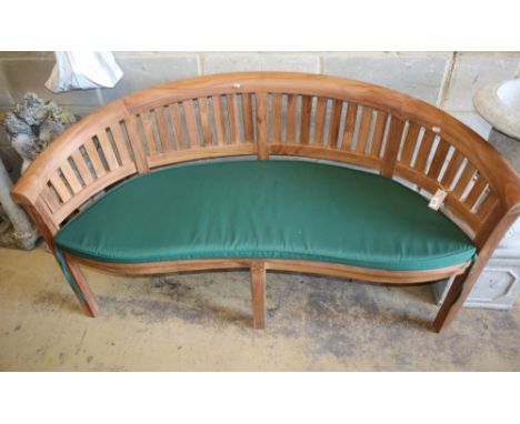 A teak garden banana bench with cushion seat, W.160cm, D.54cm, H.85cm