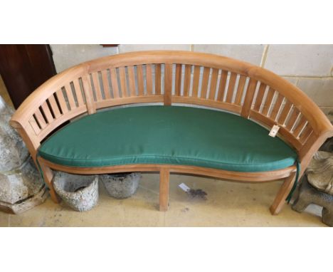 A teak garden banana bench with cushion seat, W.160cm, D.54cm, H.85cm