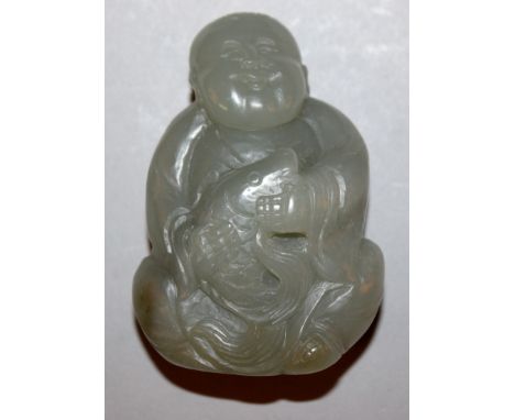 A CHINESE JADE-LIKE FIGURE OF A BOY HOLDING A FISH, the stone of grey-green hue, 2.5in high.