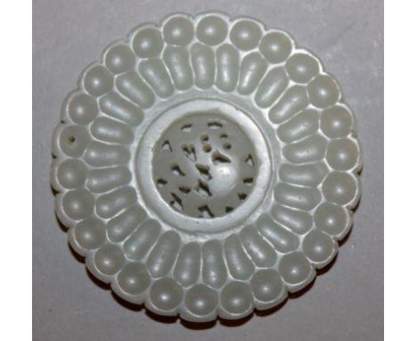 A CHINESE WHITE JADE-LIKE FLOWER FORM ROUNDEL, incorporating a central pierced moveable disc, 2.2in diameter.