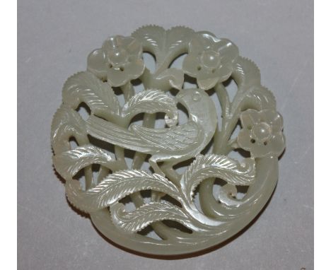 A DEEP CHINESE CELADON JADE SHAPED CIRCULAR PLAQUE, carved and pierced with a bird amidst flowers and leafage, 2.4in diameter