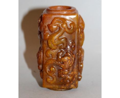 A SMALL CHINESE JADE-LIKE CONG, the brown body with paler inclusions and decorated in high relief to each side with a pair of