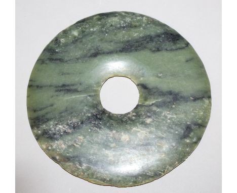 A LARGE CELADON GREEN JADE BI DISC, the stone with lighter and darker inclusions, 7.9in diameter.