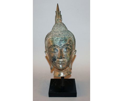 A THAI BRONZE HEAD OF BUDDHA, of larger than average size, mounted on a wood base, the whole with a patinated finish, 16.6in 