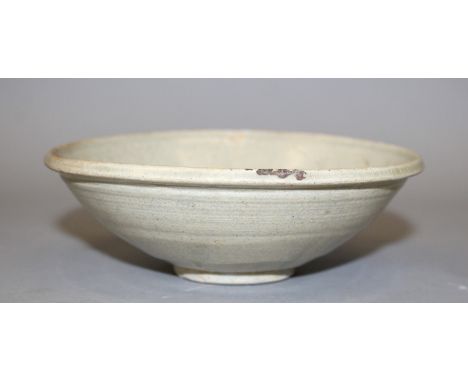 A CHINESE SONG DYNASTY CERAMIC BOWL, applied with a pale lightly speckled glaze, the base unglazed, 6in diameter.