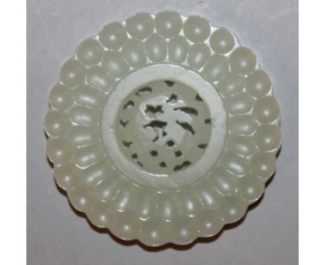 A SIMILAR SMALLER CHINESE WHITE JADE-LIKE FLOWER FORM ROUNDEL, incorporating a central pierced moveable disc, 2in diameter.