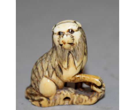 AN 18TH CENTURY JAPANESE EDO PERIOD CARVED IVORY NETSUKE OF A KARASHISHI, the maned lion-dog seated on rockwork with one paw 