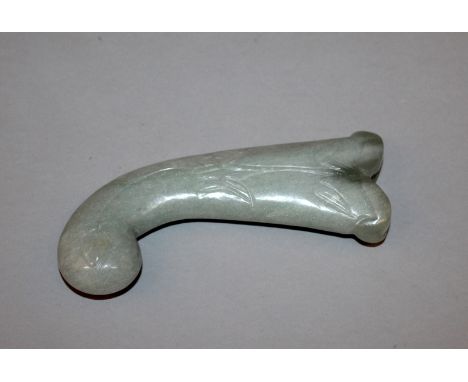 A MUGHAL CELADON JADE-LIKE HANDLE, of curving form, each side carved with a foliate spray, 5.75in long.