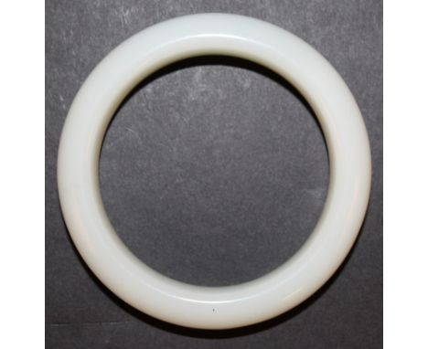 A CHINESE WHITE JADE-LIKE BANGLE, possibly glass, 3.1in diameter, the inner rim 2.25in diameter.