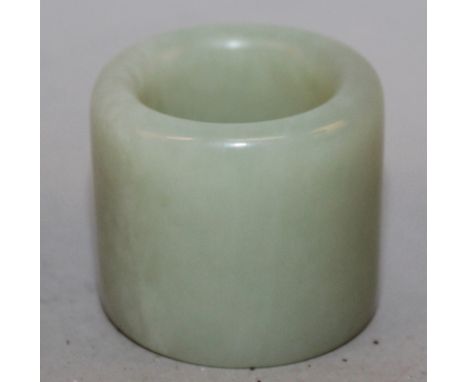 A CHINESE CELADON JADE-LIKE ARCHERS RING, 1.1in long & 1.3in diameter.