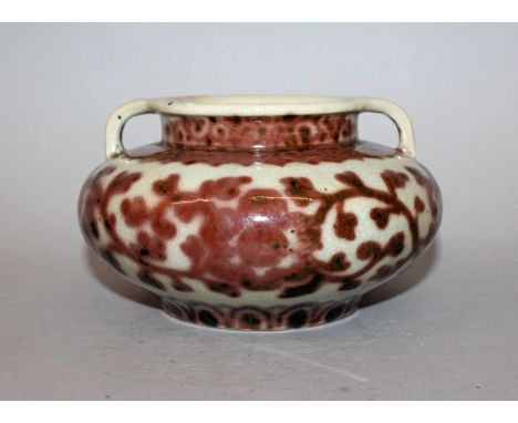 A CHINESE UNDERGLAZE-RED PORCELAIN VASE, of squat form with double lug handles, the sides decorated with scroll-stemmed flowe