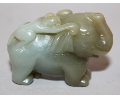 A CHINESE DARK CELADON JADE-LIKE MODEL OF AN ELEPHANT, a monkey clambering on its back, 2.25in long & 1.6in high.