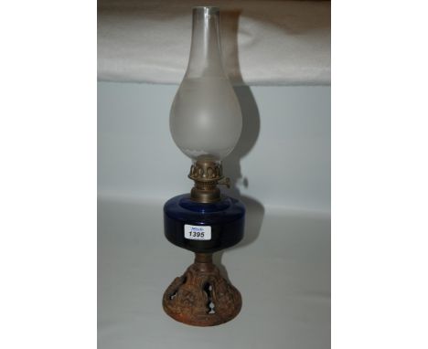An Oil Lamp with cast base,lion head detail and blue reservoir and frosted chimney.