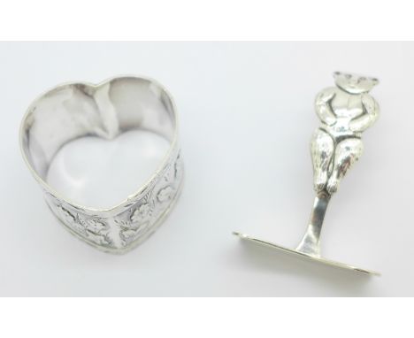 A heart shaped silver napkin ring and a silver baby's food pusher designed with a Teddy bear, 39g