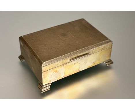 A Birmingham silver rectangular cigarette box with engine turned cover and cedar lined interior on bracket feet and weighted 
