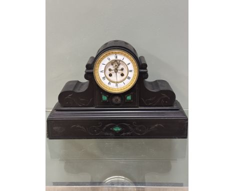 A black slate mantle clock, with green marble inserts, with a circular white enamel dial with Roman numerals and visible anch
