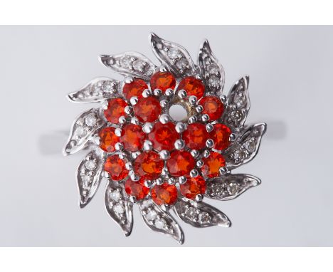 A 9ct white gold cluster style ring set with small round cut diamonds and small round orange stones (possibly fire opal? One 