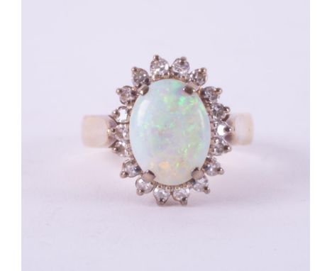 A 14ct yellow gold cluster ring set with a central cabochon cut opal, measuring approx. 11mm x 8.5mm x 3mm (depth measured wi