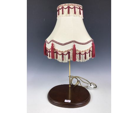 A contemporary table lamp with a cream and red shade