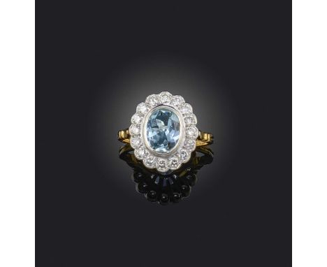 An aquamarine and diamond ring, of cluster design, set with an oval aquamarine, within a border of brilliant-cut diamonds, mo