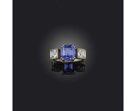 A tanzanite and diamond three stone ring, set with a cushion-shaped tanzanite flanked with old cushion-shaped diamonds in whi